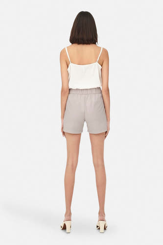 Grijze short van JDY, gezien van achteren, met elastische tailleband en gecombineerd met een witte top en beige hakken.
