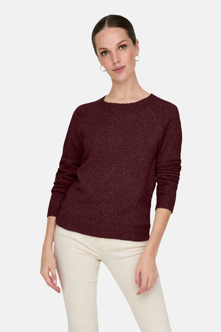 Bordeaux trui met ronde hals van ONLY, gecombineerd met een crèmekleurige broek en gouden oorringen.

