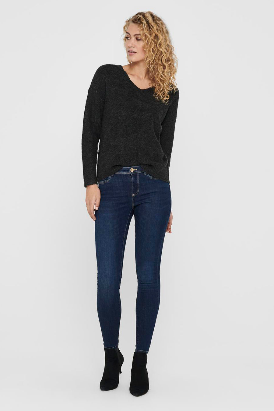 Sweat-shirt gris à col V ONLY®, manches longues, associé à des jeans skinny foncés et des mocassins noirs.