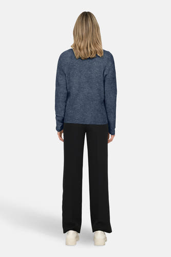 Blauwe trui met V-hals van ONLY, gedragen met een zwarte broek en witte schoenen, achteraanzicht.
