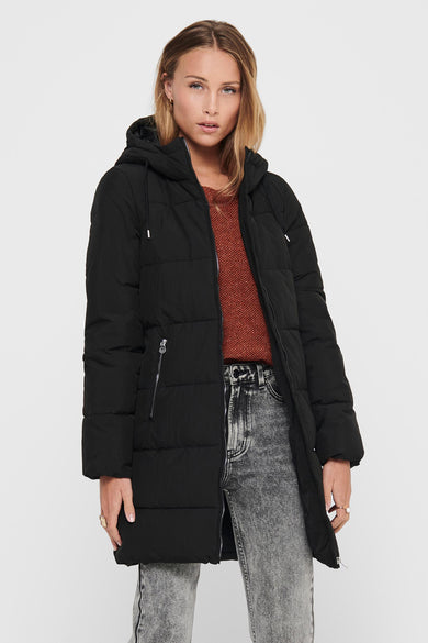Zwarte lange jas van ONLY®, met capuchon en horizontale stiksels, gedragen met een bruine trui en grijze jeans.
