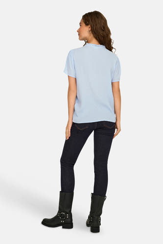 Blauwe blouse met korte mouwen van JDY met een subtiel stippenpatroon en ruches kraagje, achterkant, gedragen op donkere jeans en zwarte laarzen.