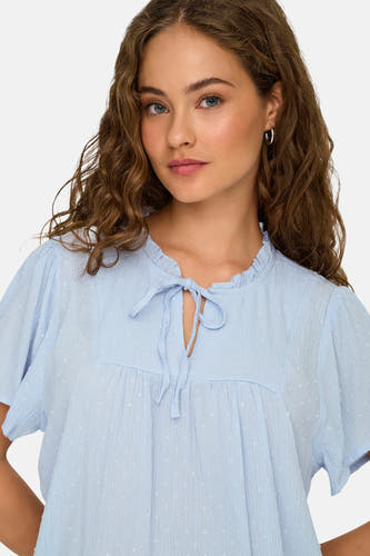 Blauwe blouse met korte mouwen van JDY, met subtiel stippenpatroon, rucheskraag en strikdetail.