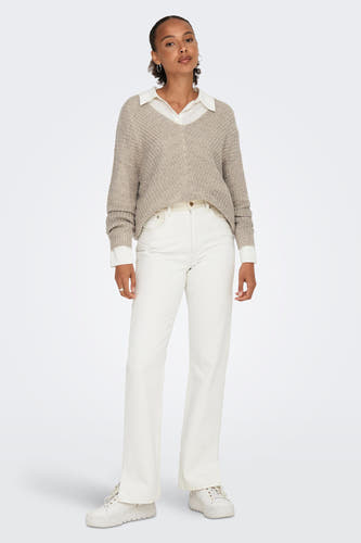 Pull marron avec col V de JDY, porté sur une chemise blanche, associé à des jeans blancs et des baskets sur plateforme.