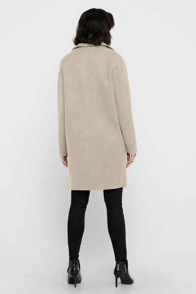 Beige lange jas van ONLY, gezien van achteren, met zwarte broek en hakken.
