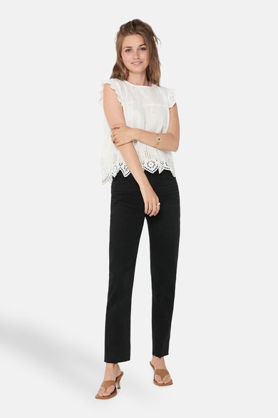 Witte mouwloze blouse van ONLY, met broderie details en gedragen met zwarte jeans en bruine hakken.
