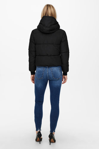 Dos d'un personne en un veste en fourrure noire et un pantalon marron.