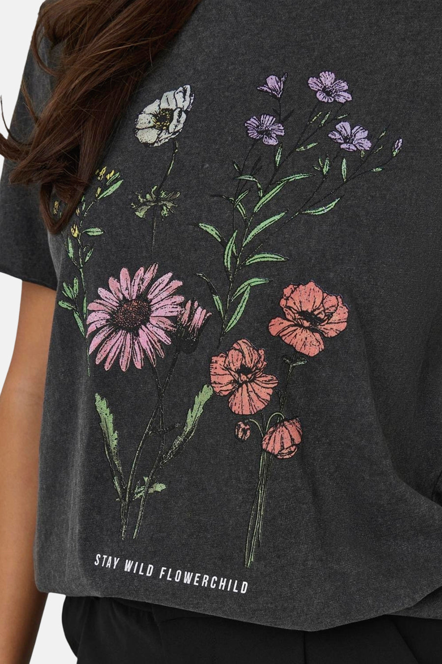 T-shirt noir à manches courtes de ONLY, avec un imprimé de fleurs et le texte 'Stay wild flowerchild'.
