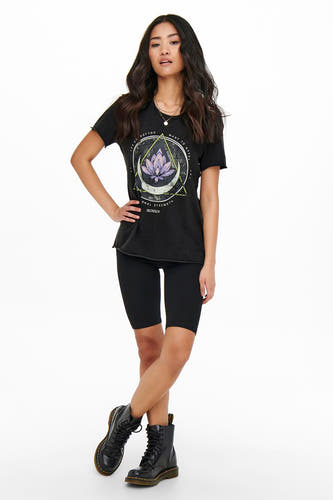 Zwart T-shirt van ONLY, met een paarse lotusbloem print en korte mouwen, gecombineerd met zwarte korte legging en stoere boots.
