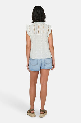 Witte mouwloze blouse van ONLY, met broderie details en gecombineerd met denim shorts en sandalen met sleehak.
