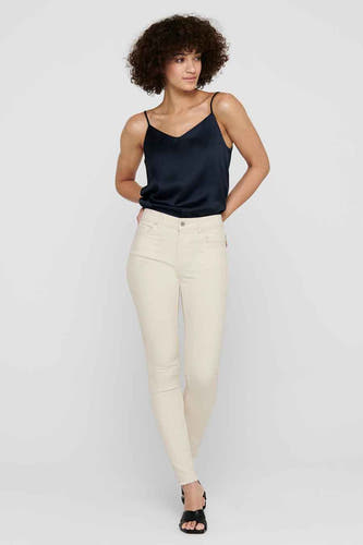 Jean skinny beige de ONLY, porté avec un haut en soie et des sandales.