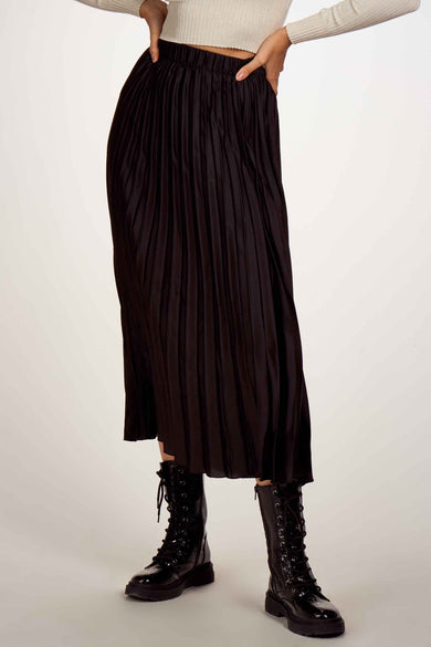 Jupe noire 3/4 de ONLY® avec plis verticaux, taille élastique, portée avec un pull beige et des bottes noires, vue de face