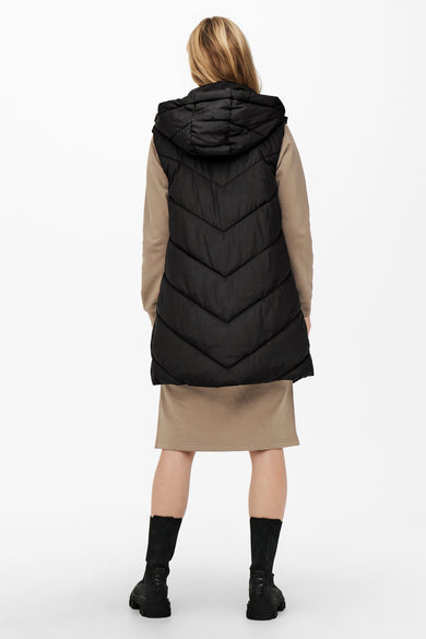 Gilet chauffant noir de JDY, avec capuche, associé à une jupe beige et des bottes noires.