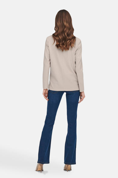 Beige blazer van JDY, gezien van achteren, met lange mouwen en gecombineerd met een donkere jeans en hakken.
