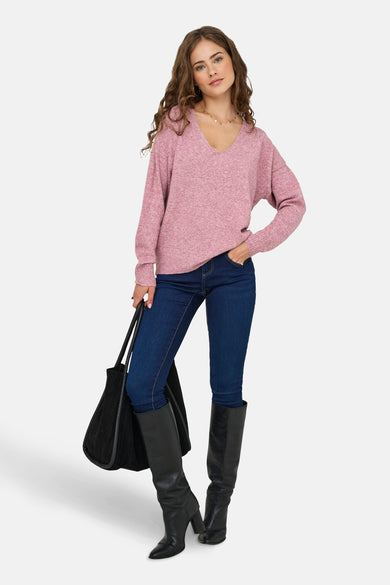 Blouse rose à col V d'ONLY, portée avec des jeans foncés, des bottes noires et une sacoche noire.
