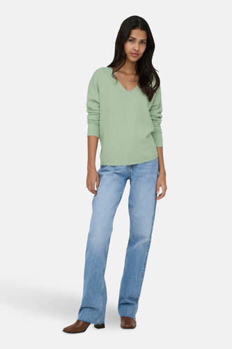 Groene trui met V-hals van ONLY, gedragen met blauwe jeans en bruine laarzen.