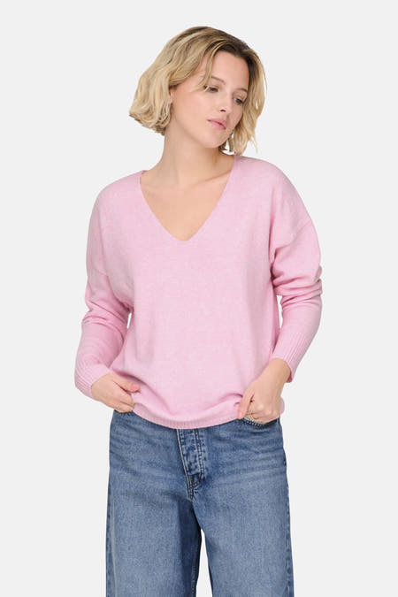 Roze trui met V-hals van ONLY, gedragen met blauwe jeans.
