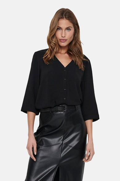 Zwarte blouse met driekwart mouwen van JDY, gedragen met een zwarte leren rok en riem.
