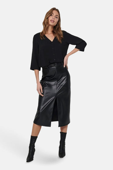 Zwarte blouse van JDY, met V-hals en driekwart mouwen, gecombineerd met een leren rok met split en laarzen.
