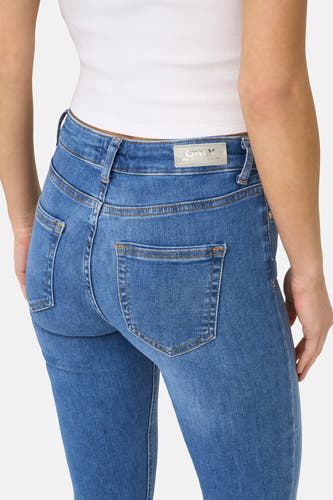 Middenblauwe skinny jeans van ONLY, met achterzakken en een witte top.