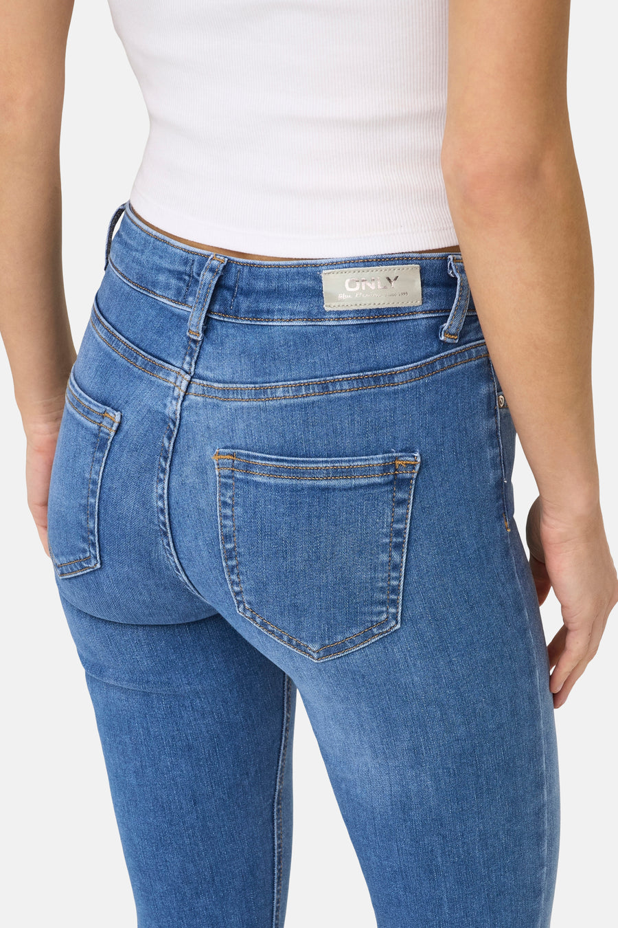 Middenblauwe skinny jeans van ONLY, met achterzakken en een witte top.