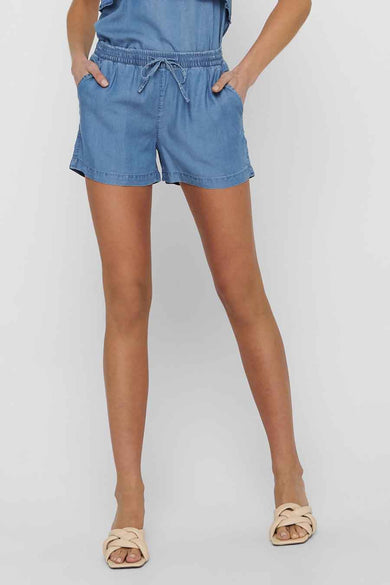 Mid-blauwe denim shorts van ONLY® met elastische taille en trekkoord, gestyled met een denim top en beige gevlochten sandalen.