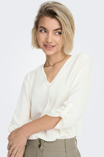 Witte blouse van JDY, met driekwart mouwen, gouden ketting en oorbellen, en bruine pantalon.