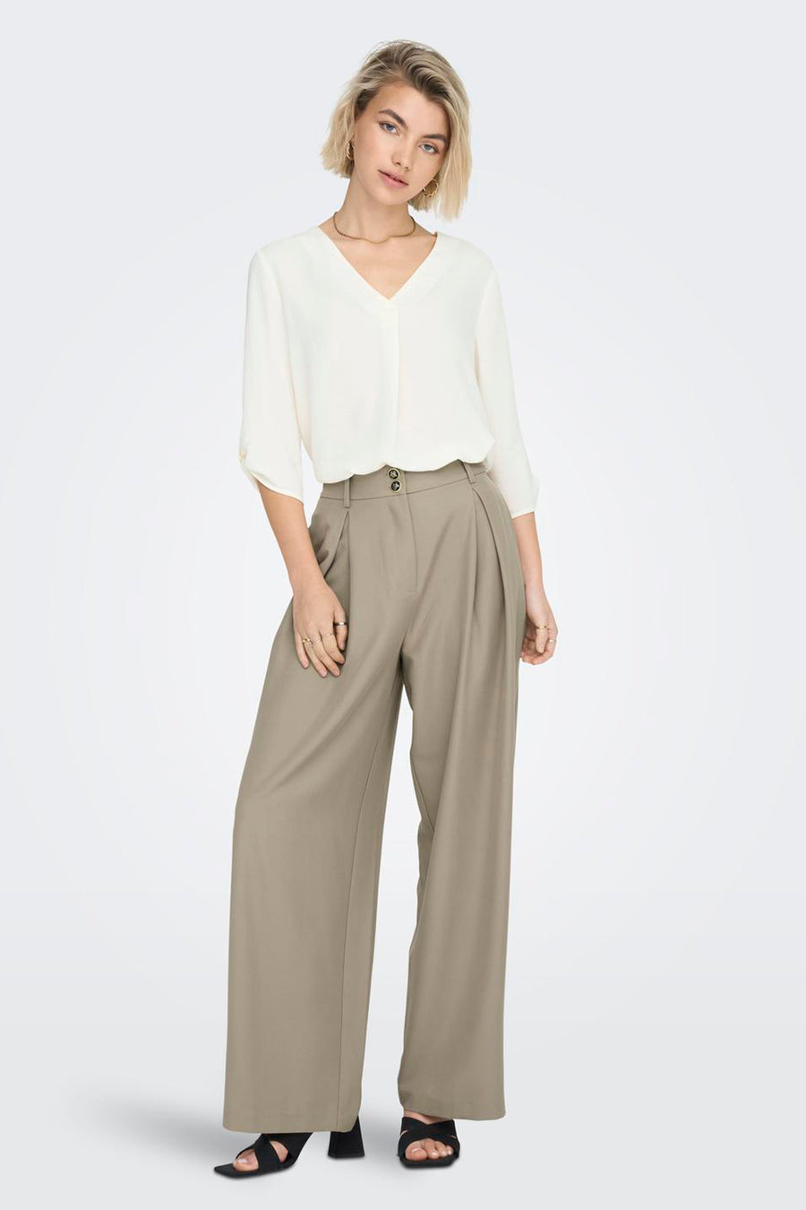 Witte blouse met driekwart mouwen van JDY, met V-hals en gedragen met een khaki pantalon en sandalen.
