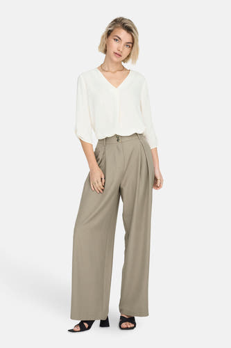 Witte blouse met driekwart mouwen van JDY, gedragen met wijde, olijfgroene pantalon en zwarte sandalen.