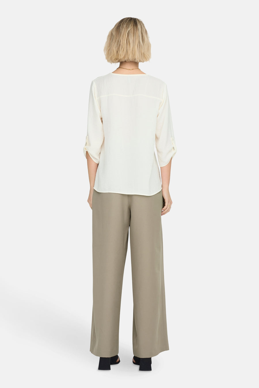 Witte blouse met driekwartmouwen van JDY, gezien van achteren, met lange groene broek en gouden ketting.