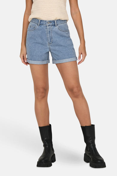 Denim short in lichtblauw, van ONLY, met opgerolde zoom en gecombineerd met zwarte laarzen.
