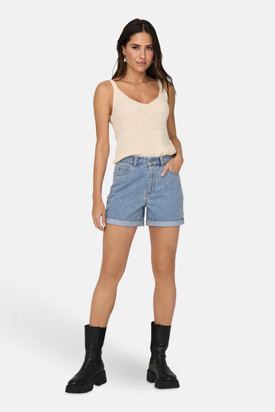 Korte broek van lichtblauw denim van ONLY, gedragen met een gebreide top en zwarte laarzen.
