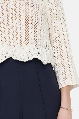 Ecru trui van ONLY met opengebreid patroon en driekwart mouwen, gedragen over een donkerblauwe broek en gouden armband.
