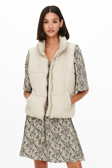 Ecru bodywarmer van JDY, gecombineerd met een paisley-jurk, met steekzakken en een opstaande kraag.