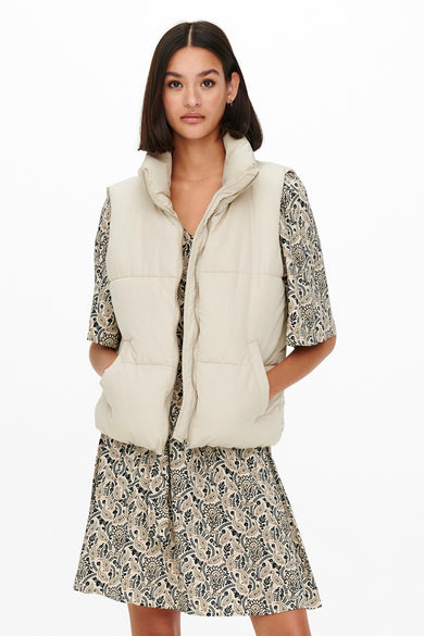 Ecru bodywarmer van JDY, gecombineerd met een paisley-jurk, met steekzakken en een opstaande kraag.