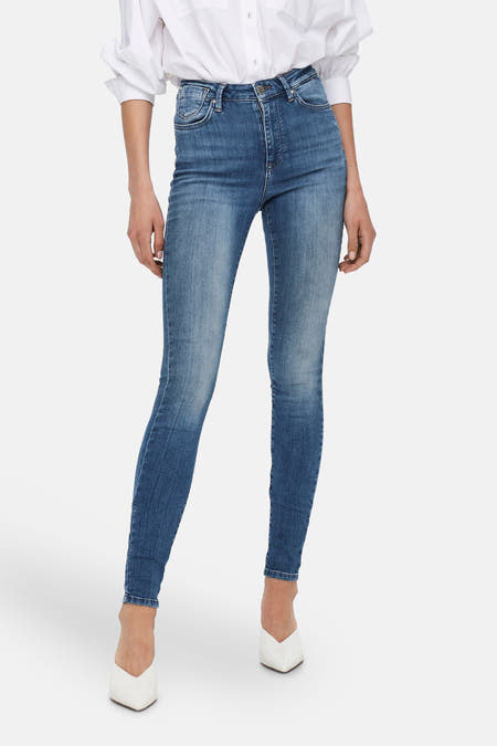 Mid blue skinny jeans van ONLY, gecombineerd met een wit overhemd en witte hakken.
