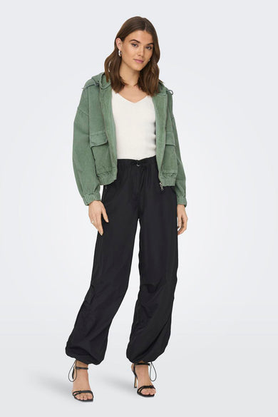 Groene korte jas van ONLY, met lange mouwen en zakken, gedragen met een witte top en zwarte broek.
