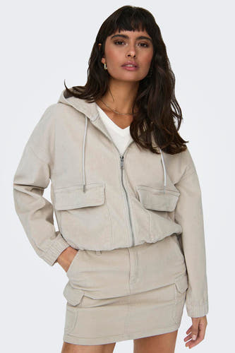 Ecru korte jas van ONLY, met capuchon, rits en zakken; gecombineerd met een ecru rok.
