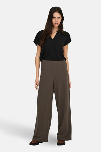Zwarte blouse van JDY met korte mouwen en een V-hals, gedragen met een donkere broek met wijde pijpen.