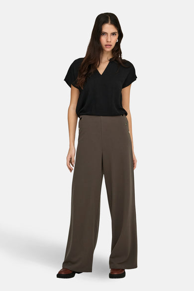 Zwarte blouse van JDY met korte mouwen en een V-hals, gedragen met een donkere broek met wijde pijpen.