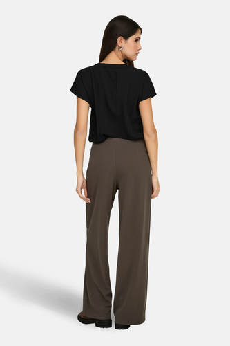 Zwarte blouse met korte mouwen van JDY, getoond op een model van achteren met bruine broek en zilveren oorbellen.