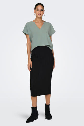 Blouse verte avec manches courtes de JDY, associée à une jupe noire et des bottines noires.