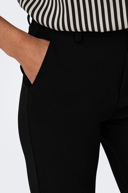Zwarte seizoensbroek voor dames van ONLY, met een hand in de zak en een gestreepte top.