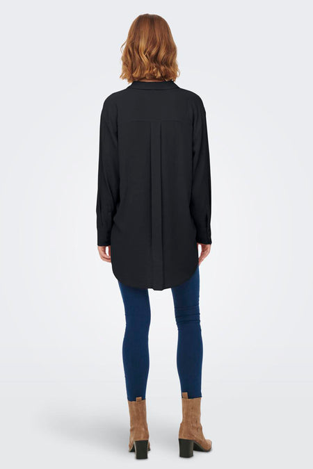 Zwart hemd met lange mouwen van JDY, met plooien op de rug, gedragen met een donkere jeans en suède laarzen.