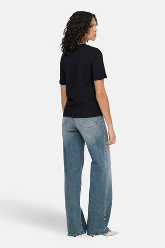 T-shirt noir ONLY, avec manches courtes et un col rond classique, porté avec un jean à pattes larges et des talons pointus.