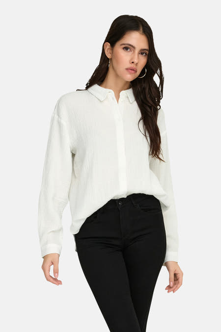 Wit hemd met lange mouwen van JDY, met een lichte textuur, gedragen met een zwarte broek en gouden oorbellen.
