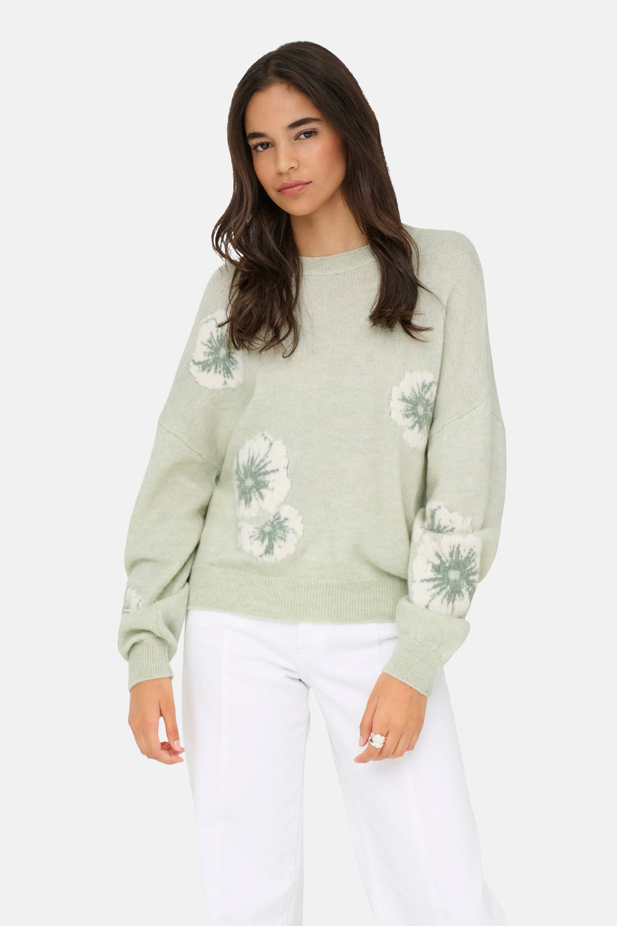 Groene trui met ronde hals van JDY, met gebloemd patroon en lange mouwen, gedragen met een witte broek.
