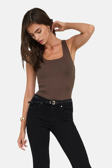 Bruine top met spaghettibandjes van ONLY, gecombineerd met zwarte jeans en een smalle riem.