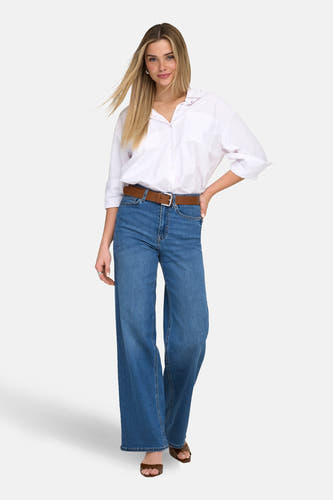 MADISON BLUSH mid blue denim jeans wide van ONLY, gecombineerd met een witte blouse en bruine riem.

