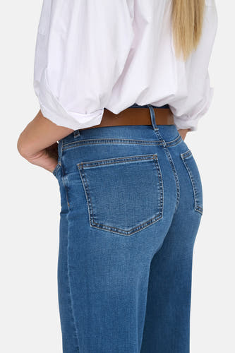 Jean large en denim bleu moyen d'ONLY, avec ceinture marron et blouse blanche.